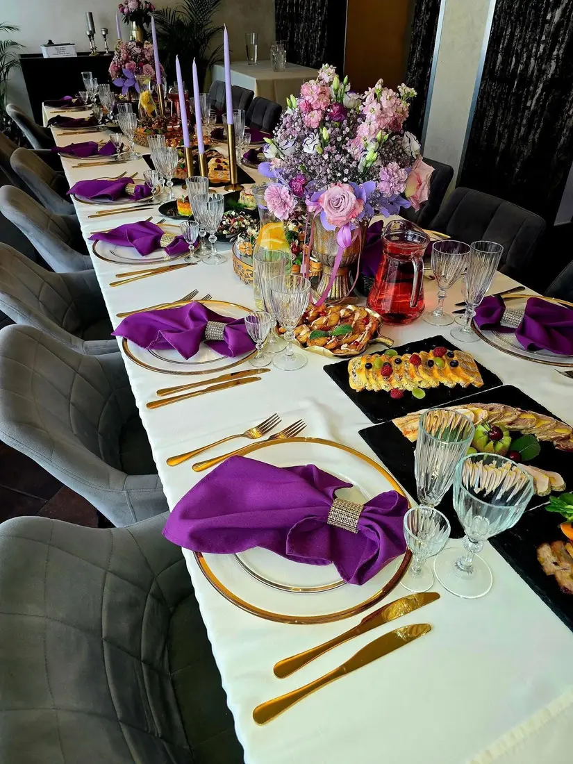 Banketo stalas su violetinėmis servetėlėmis ir gėlėmis